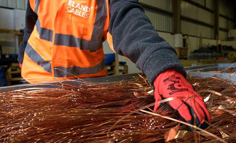 A gloved hand recycling copper at Eland Cables recycling facility