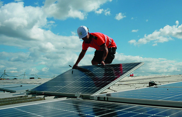A technician installing solar panels on Eland Cables' roof